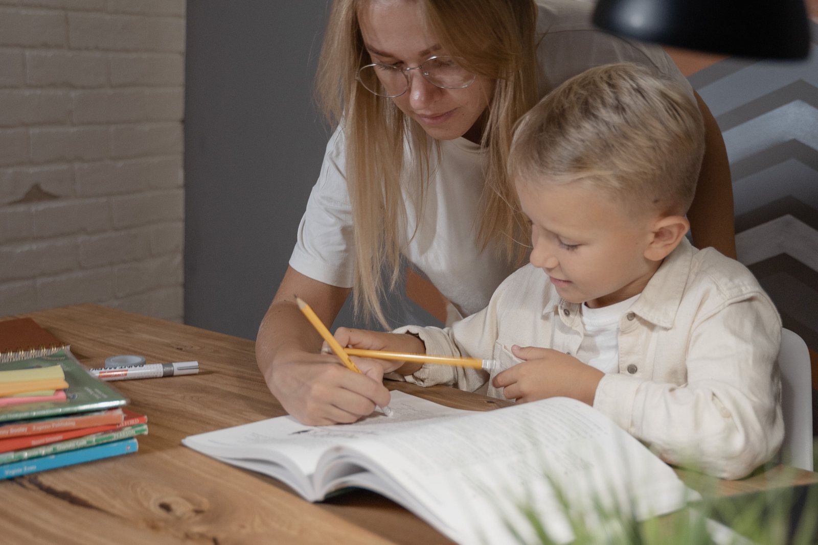 A tutor helping a young child write in an exercise book